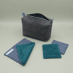 Trousse de toilette homme grise ouverte sur comptoir marbre, gel douche Ushuaia Cèdre Énergise, brosse, lingettes lavables turquoise et motifs bleus, serviette blanche monogramme M.