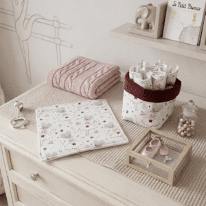 Coffret cadeau naissance "Le bal des souris" avec panier textile bordeaux, 7 lingettes lavables et une débarbouillette posés sur une commode avec un ours en peluche.