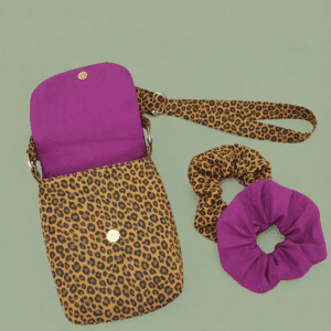 Ensemble sacoche bandoulière en coton imprimé léopard et fuchsia avec deux chouchous assortis posés sur une table.