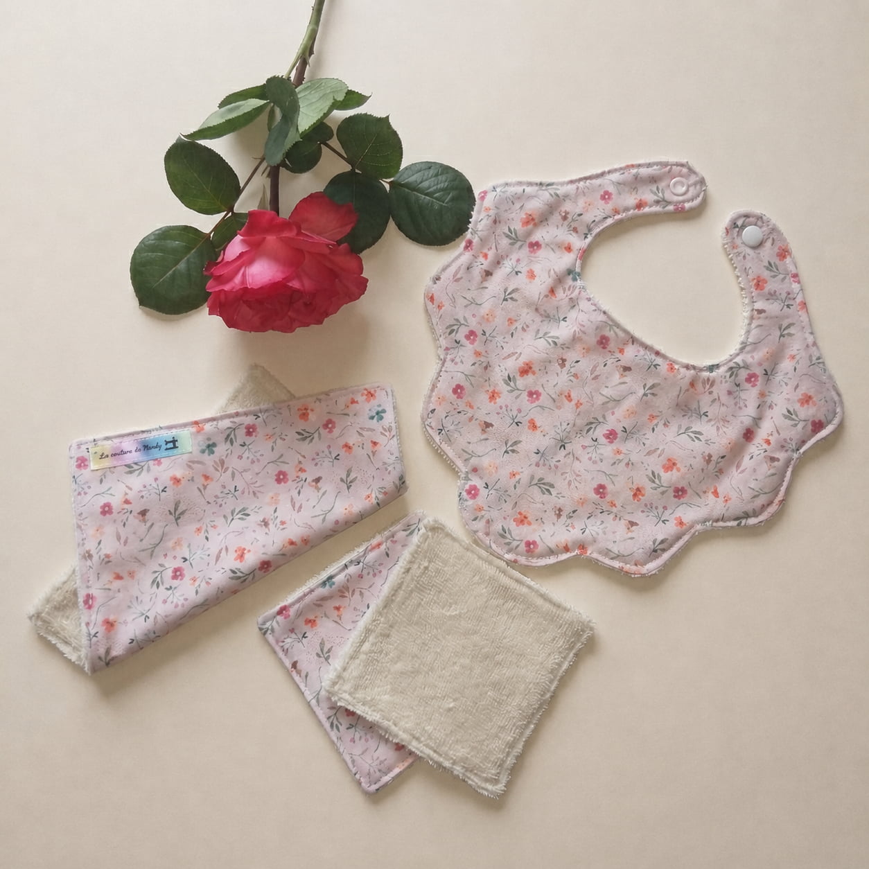 Ensemble bavoir fleur rose et lingettes réutilisables en éponge de bambou motif fleuri.