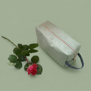 Trousse de toilette artisanale en tissu canvas couleur vert sauge avec anse bleue et rose décorative.
