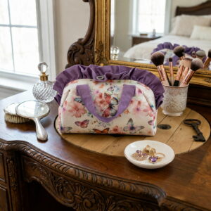 Grand vanity de maquillage en coton fleuri posé sur une coiffeuse en bois rétro à côté de pinceaux et d'un miroir.