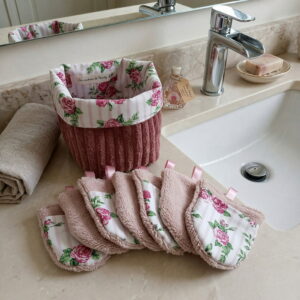 Kit de démaquillage réutilisable poudré floral posé sur le bord d'un lavabo dans une salle de bain chic