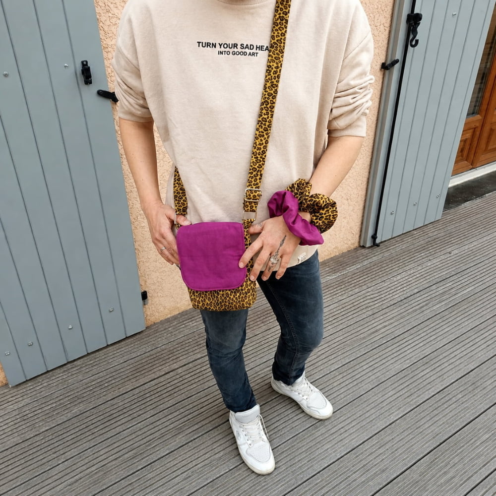 Femme portant une sacoche bandoulière léopard avec rabat fuchsia et deux chouchous assortis au poignet