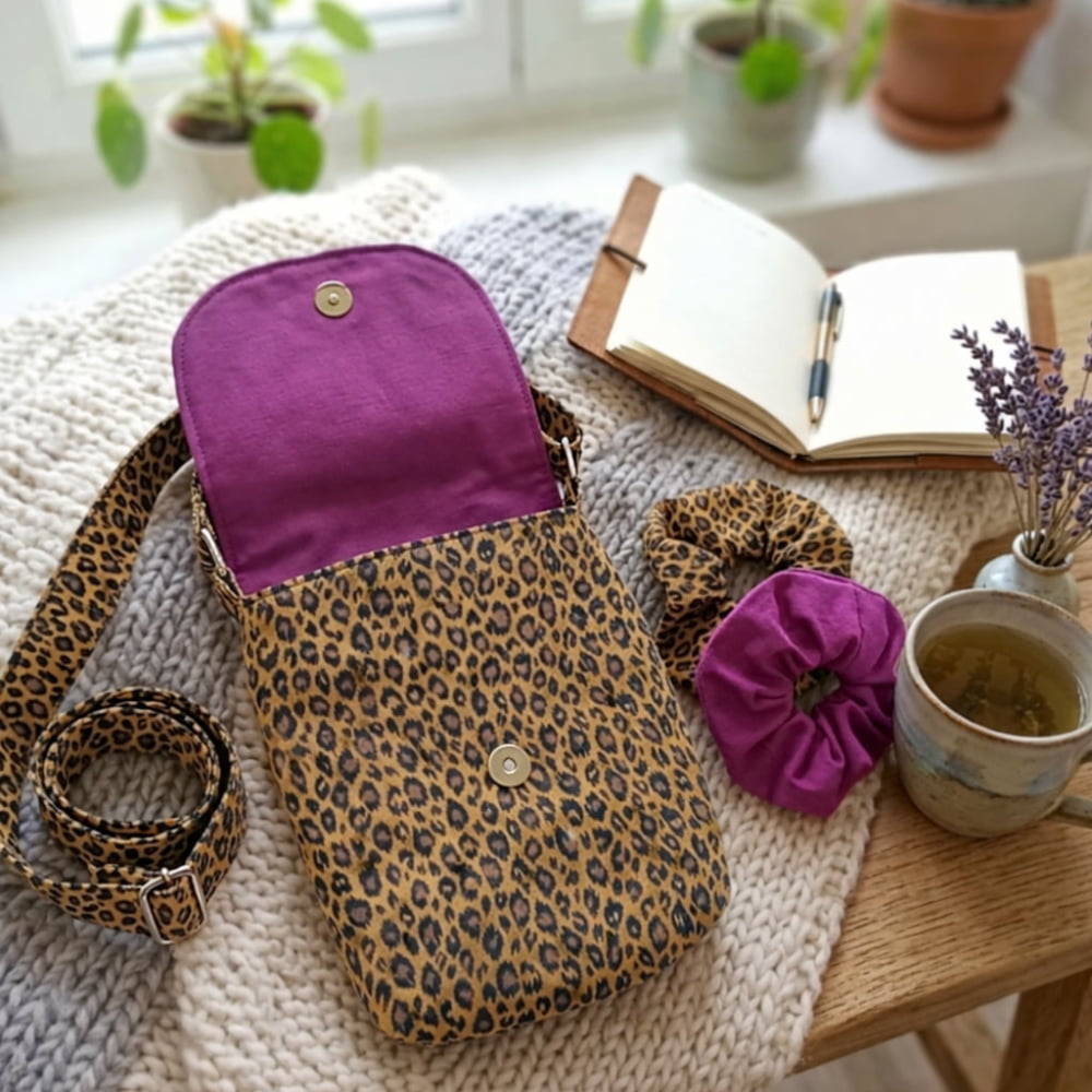 Ensemble sacoche bandoulière en coton imprimé léopard et fuchsia avec deux chouchous assortis posés sur une table