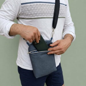 sacoche-homme-artisanale-canvas-gris-bleu Sacoche homme en canvas gris bleu portée en bandoulière sur un t.shirt blanc